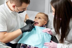 Dentist and assistant pull the tooth to the baby with forceps.