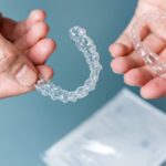 Hands holding transparent aligners. Invisalign orthodontics concept