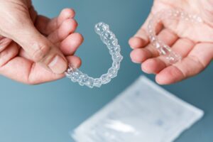 Hands holding transparent aligners. Invisalign orthodontics concept