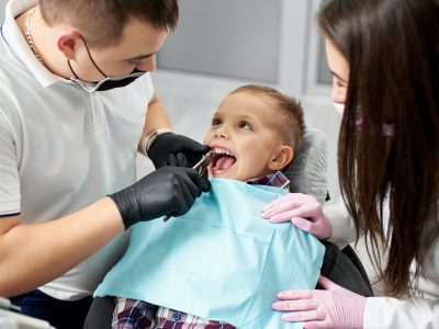 Dentist and assistant pull the tooth to the baby with forceps.