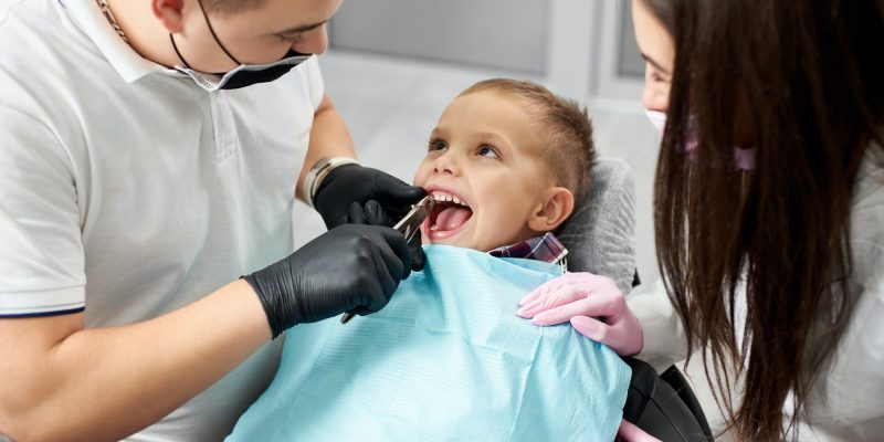 Dentist and assistant pull the tooth to the baby with forceps.