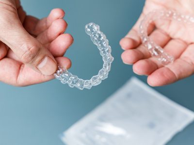 Hands holding transparent aligners. Invisalign orthodontics concept